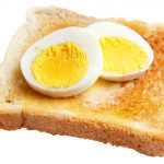 Toasted white bread with slices of hard boiled egg isolated on white ** Note: Shallow depth of field