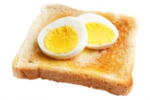 Toasted white bread with slices of hard boiled egg isolated on white ** Note: Shallow depth of field